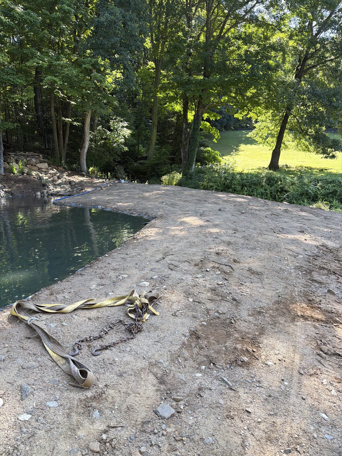 Prepared grade curving along the new pond's stone edge on a Bridgewater, CT estate, ready for tall fescue sod