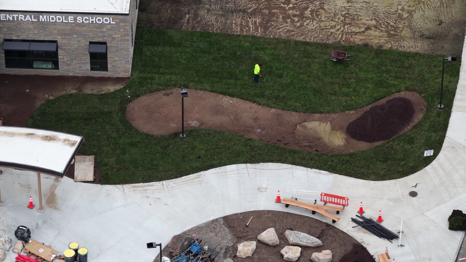 Short aerial pass over the finished building-side sod and curving landscape bed at Central Middle School in Greenwich
