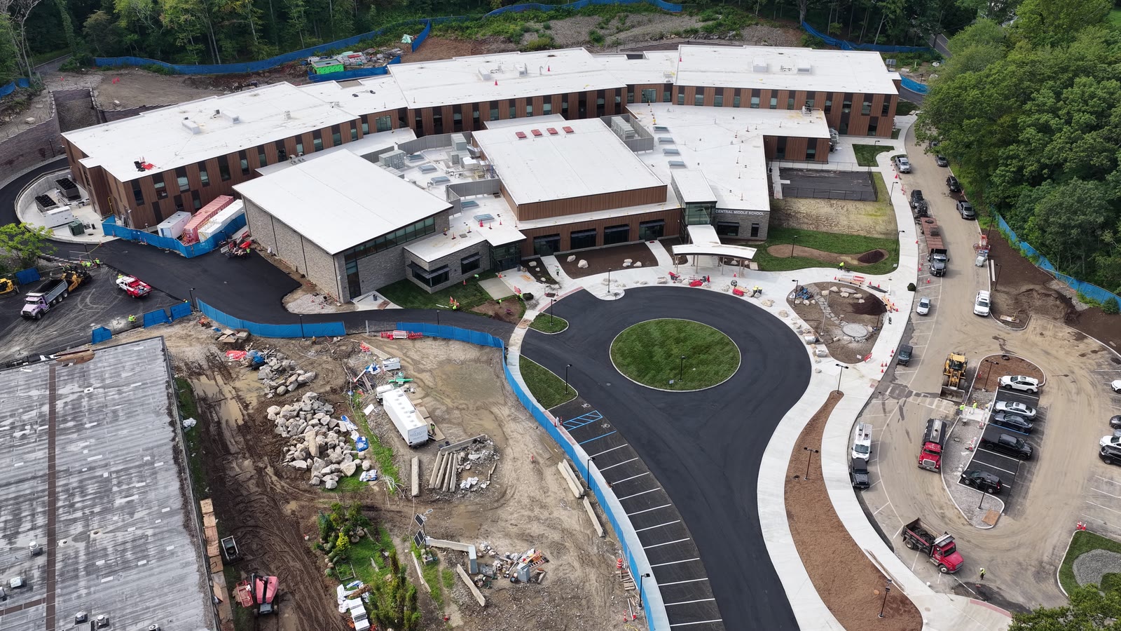 Final wide pullback over Central Middle School showing completed sod at the entrance and the surrounding construction context. Hydroseeding elsewhere is a separate landscaper scope