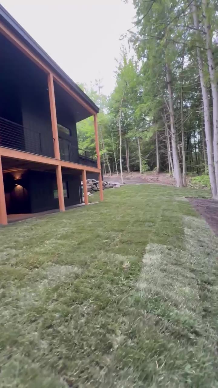 A slow pass down the full length of the new lawn beside the modern home, out toward the Vermont woods