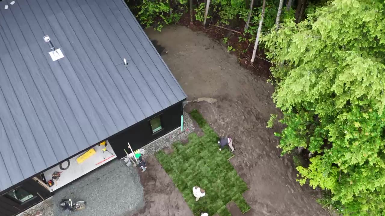 A drone pass over the site at 8:30 a.m. — the rain-soaked Quechee pad churned to mud, pallets staged and the crew already working the ground