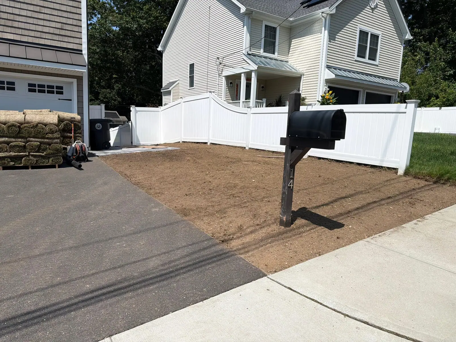 Graded front yard in Milford, CT with pallets of fresh-cut Kentucky bluegrass staged in the driveway