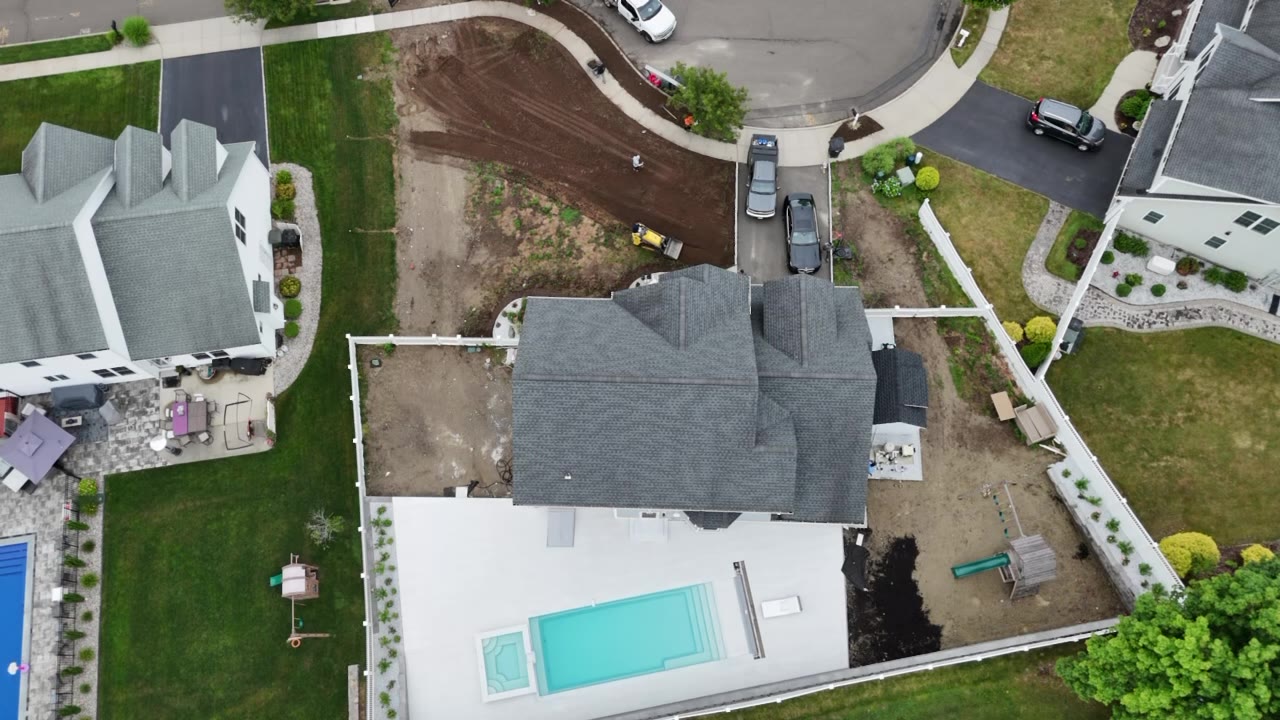 A drone pass over the whole Milford property the day before sod — graded front yard, pool and patio out back, ready for 7,000 sq ft of tall fescue