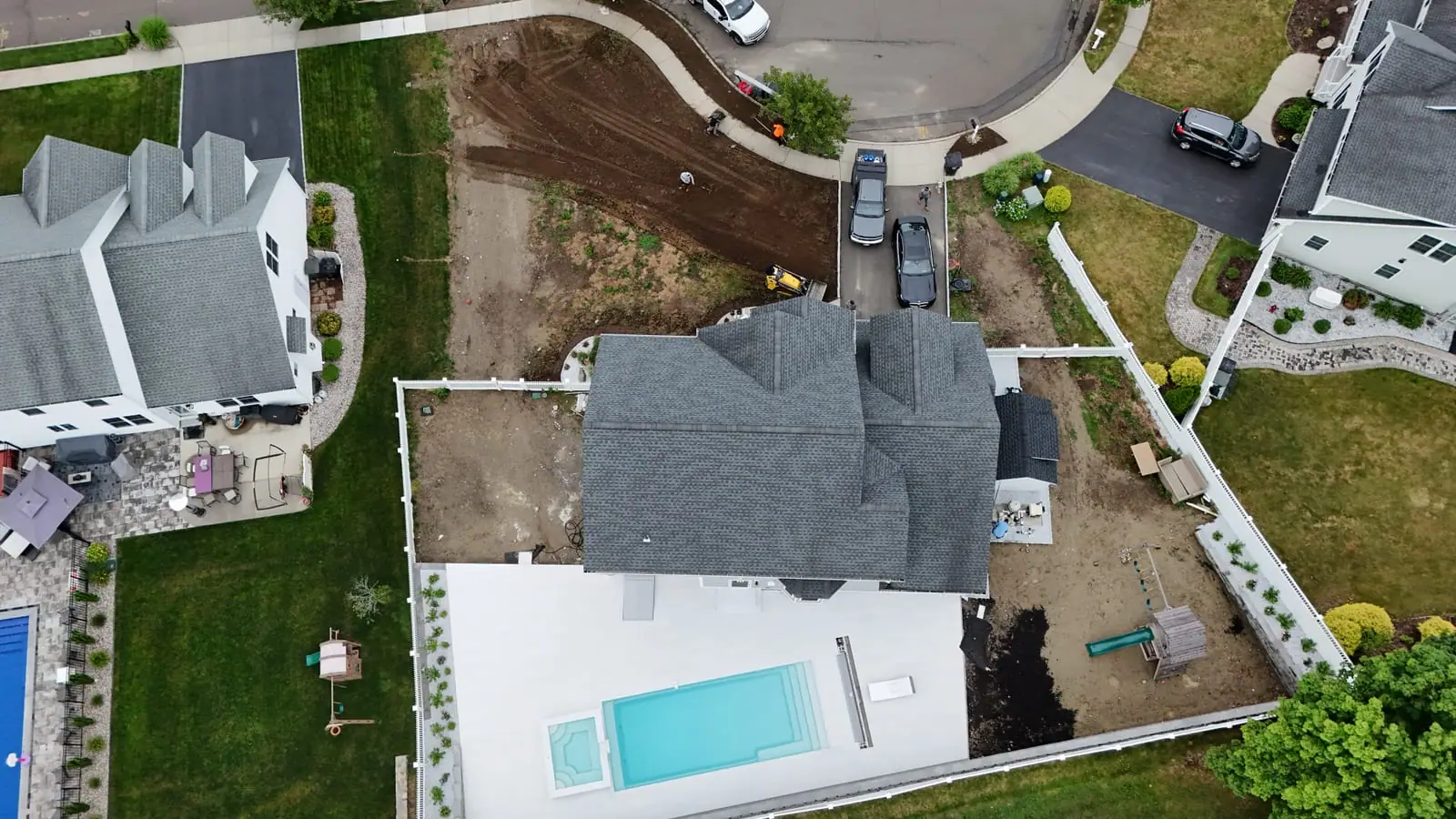 Aerial top-down view of the whole Milford, CT property before sod — the graded front yard, the in-ground pool and white patio, the playset, and the cul-de-sac