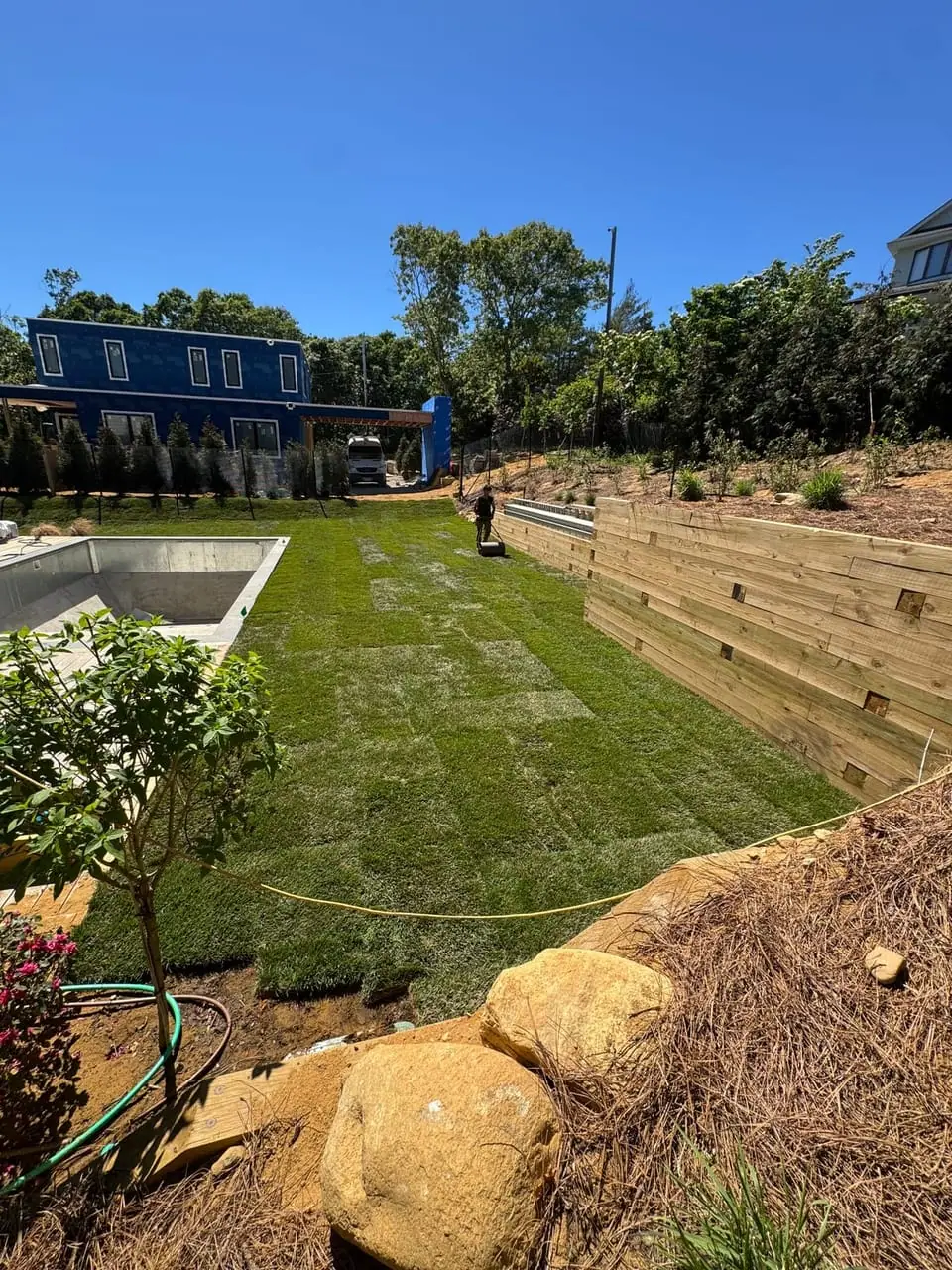 Finished green sod lawn running along the timber retaining wall after a sod installation in Montauk, NY