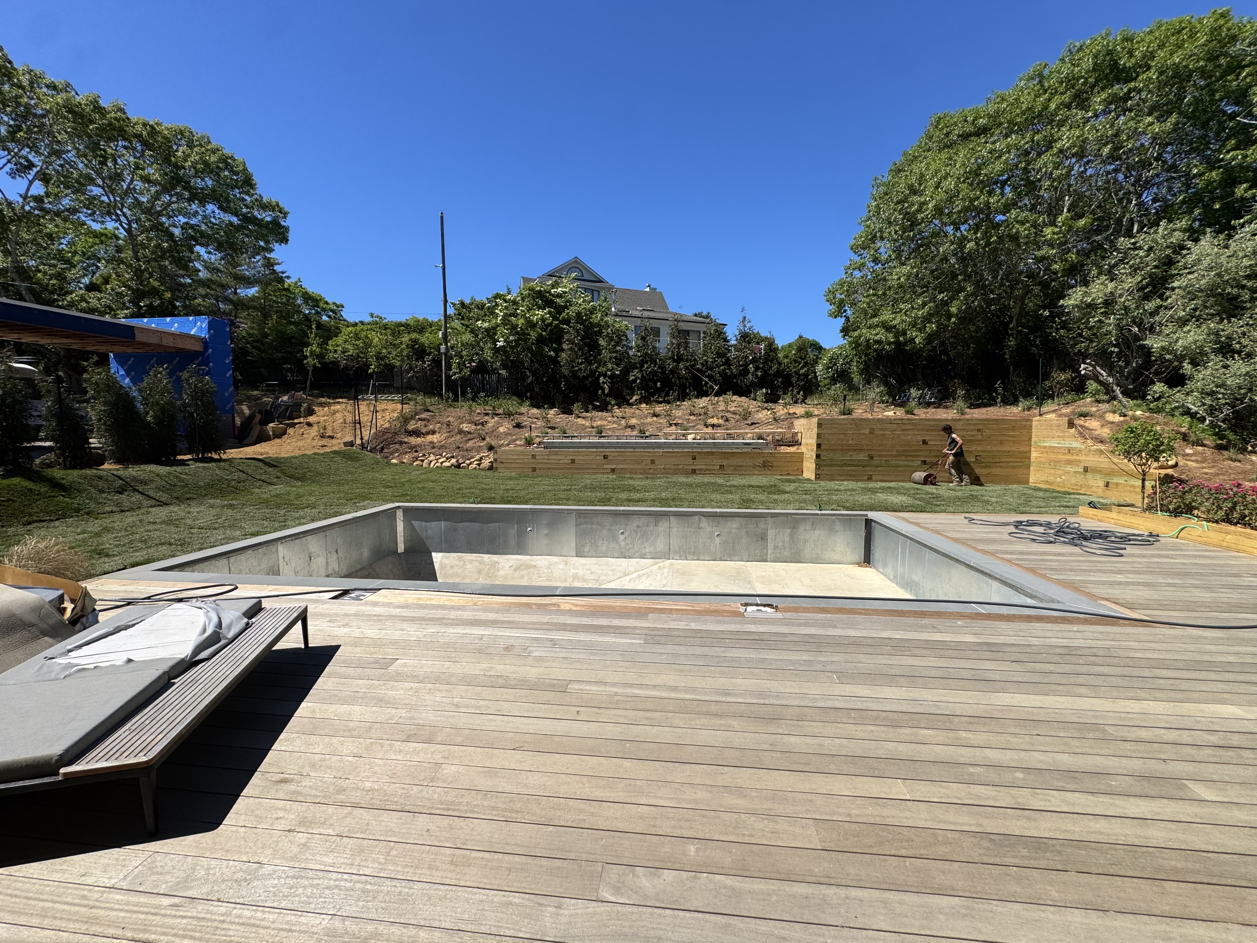 Freshly laid sod taking shape on the lawn beyond the pool deck, partway through the job