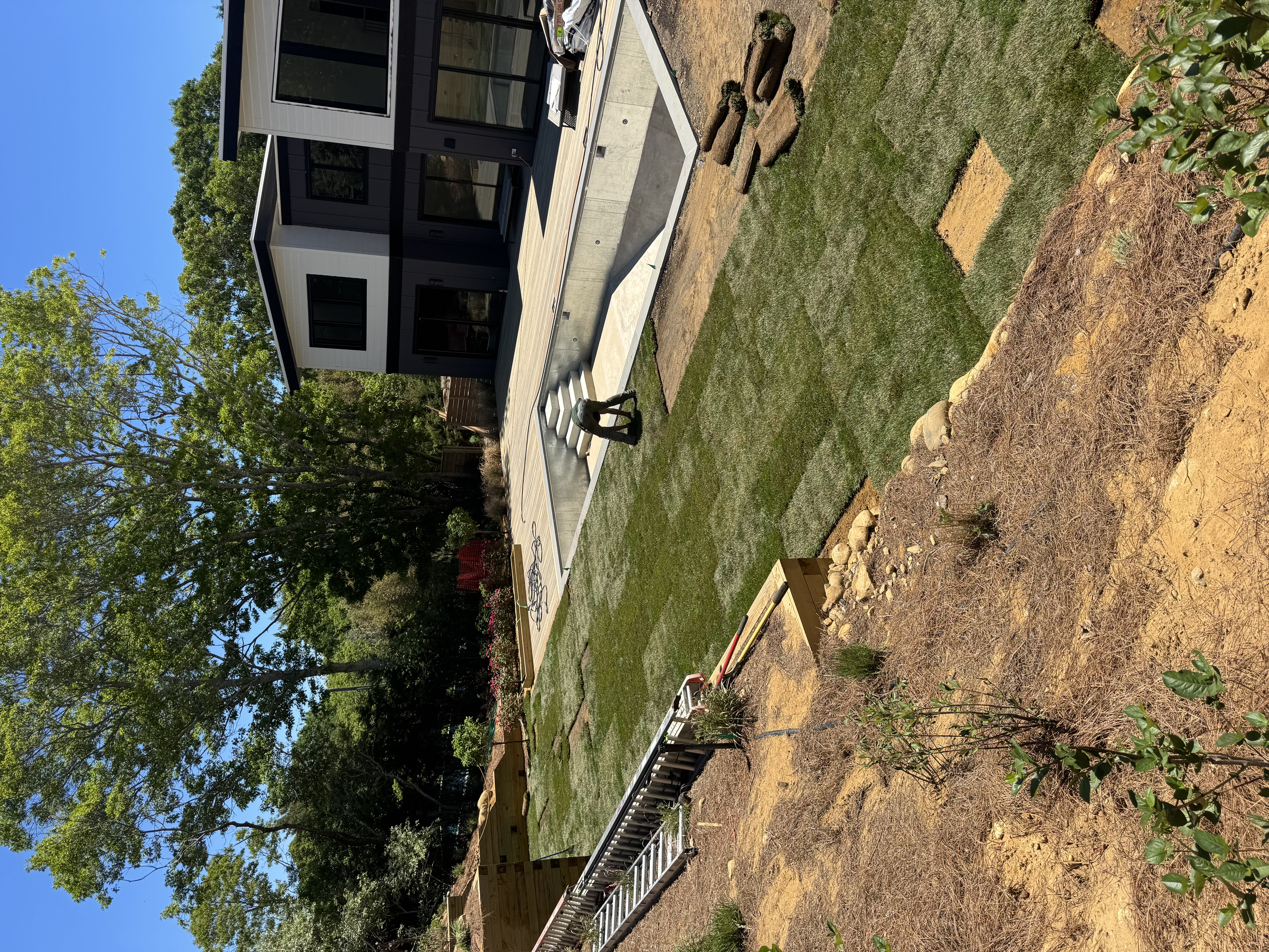 CT Sod crew laying fresh sod around the pool during a sod installation in Montauk, NY, with pallets of sod rolls staged on the new lawn