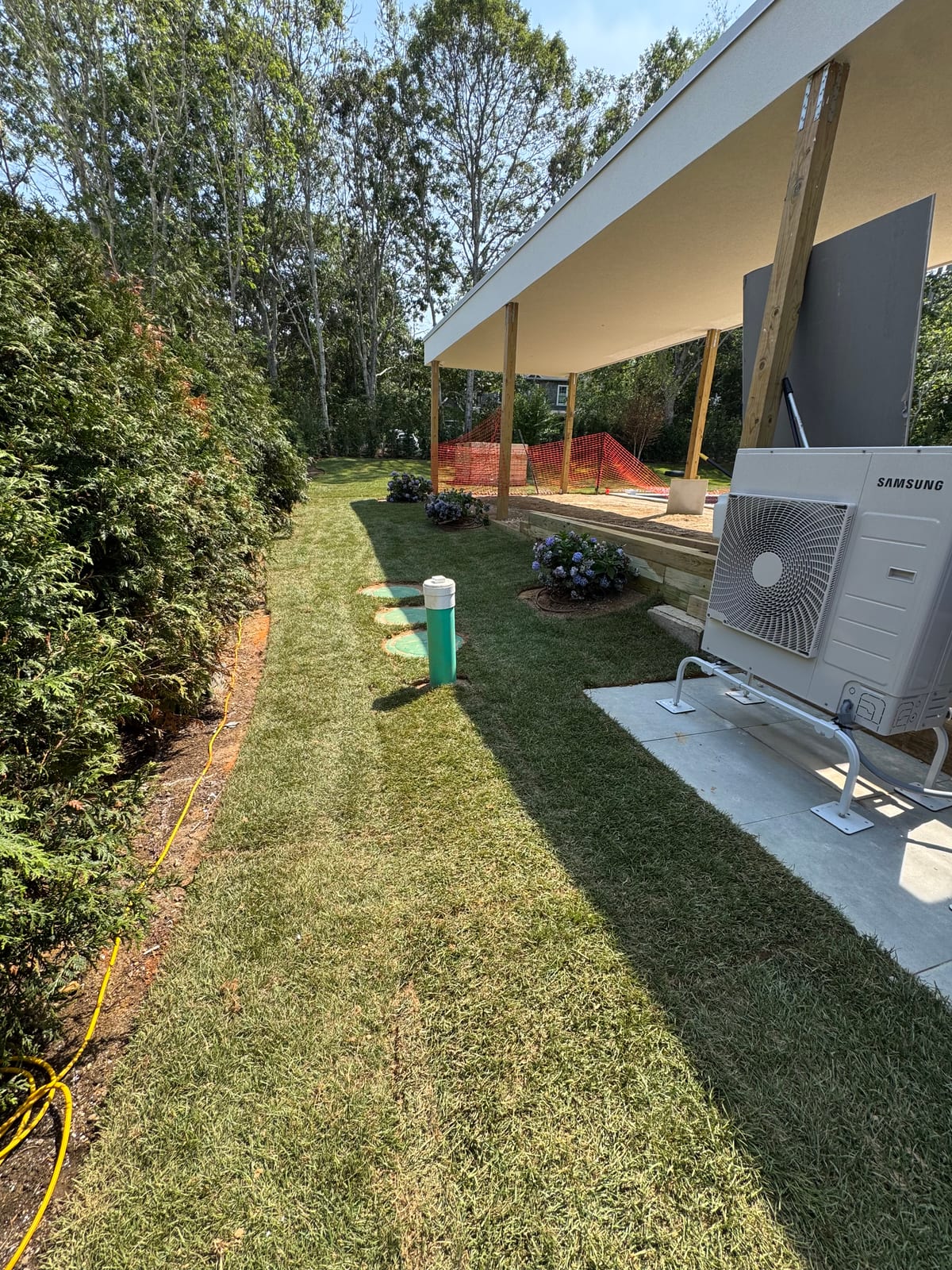 New sod running along the cedar hedge line past the heat-pump pads at the 4,500 sq ft Montauk, NY sod installation