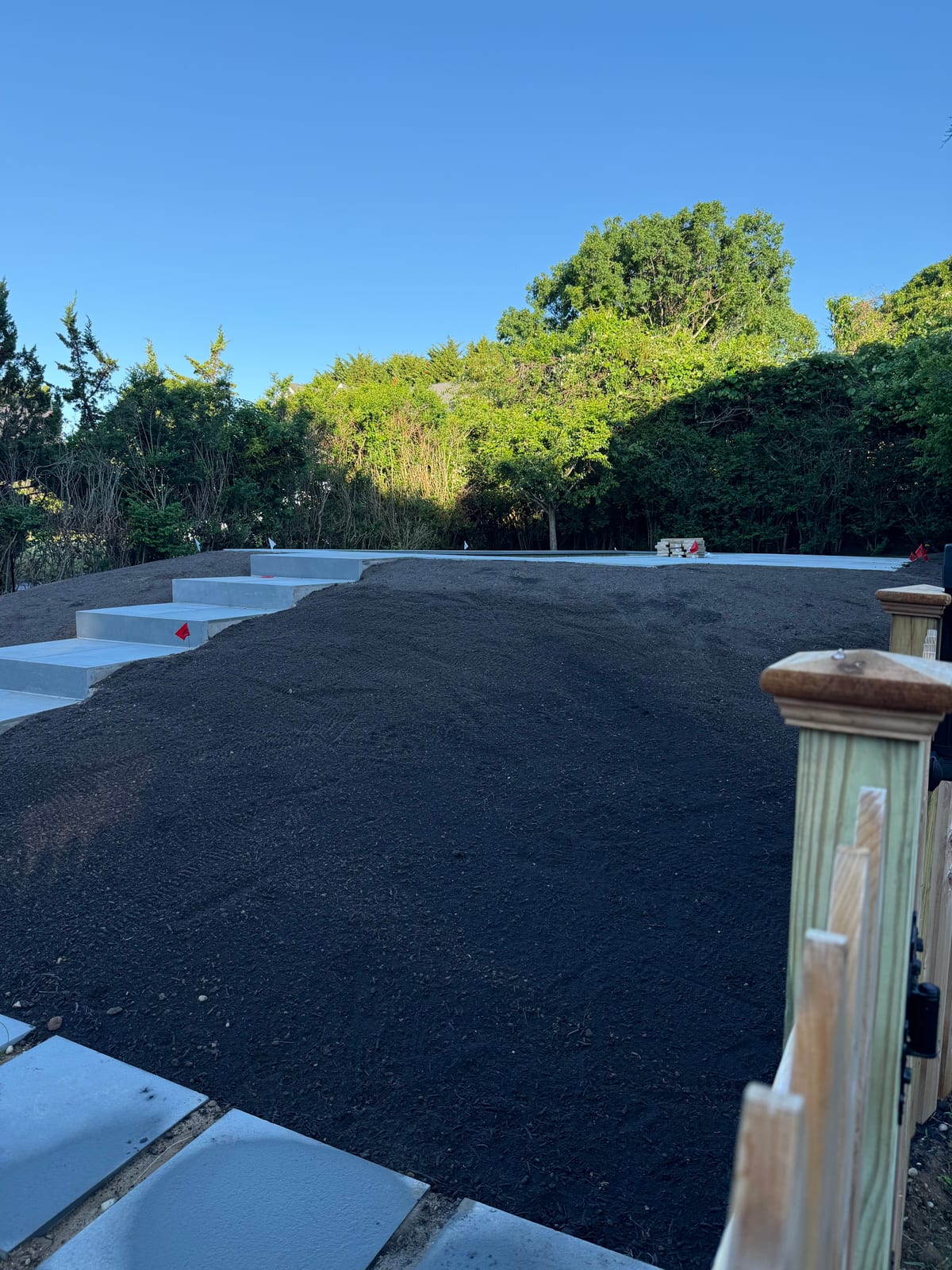 Dark, freshly graded topsoil raked to a sod-ready grade beside new bluestone steps on a Montauk, NY new build, ready for tall fescue sod