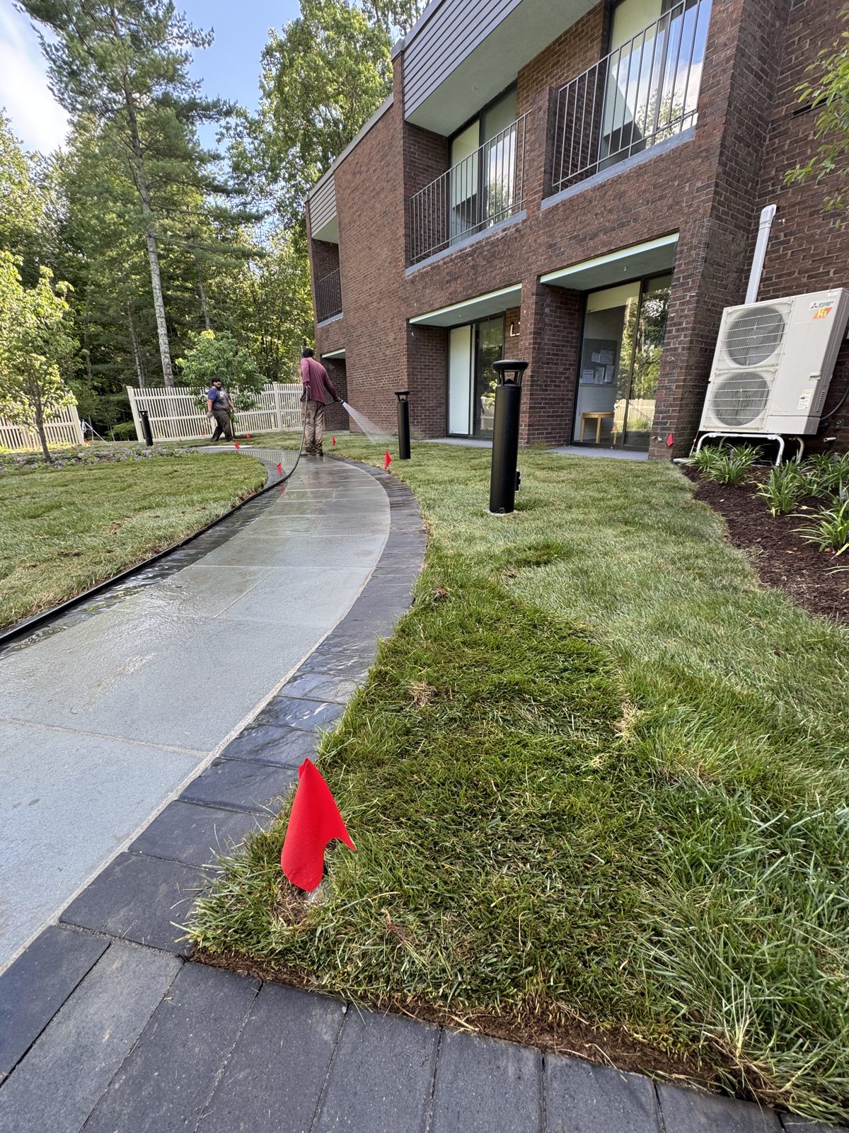 Finished Kentucky bluegrass sod along the front walk of a New Canaan, CT commercial property with a crew member watering