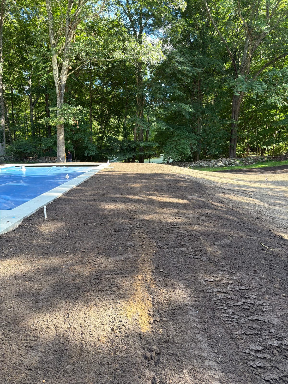 Finish-graded strip of screened topsoil beside the covered pool at the New Canaan, CT sod project