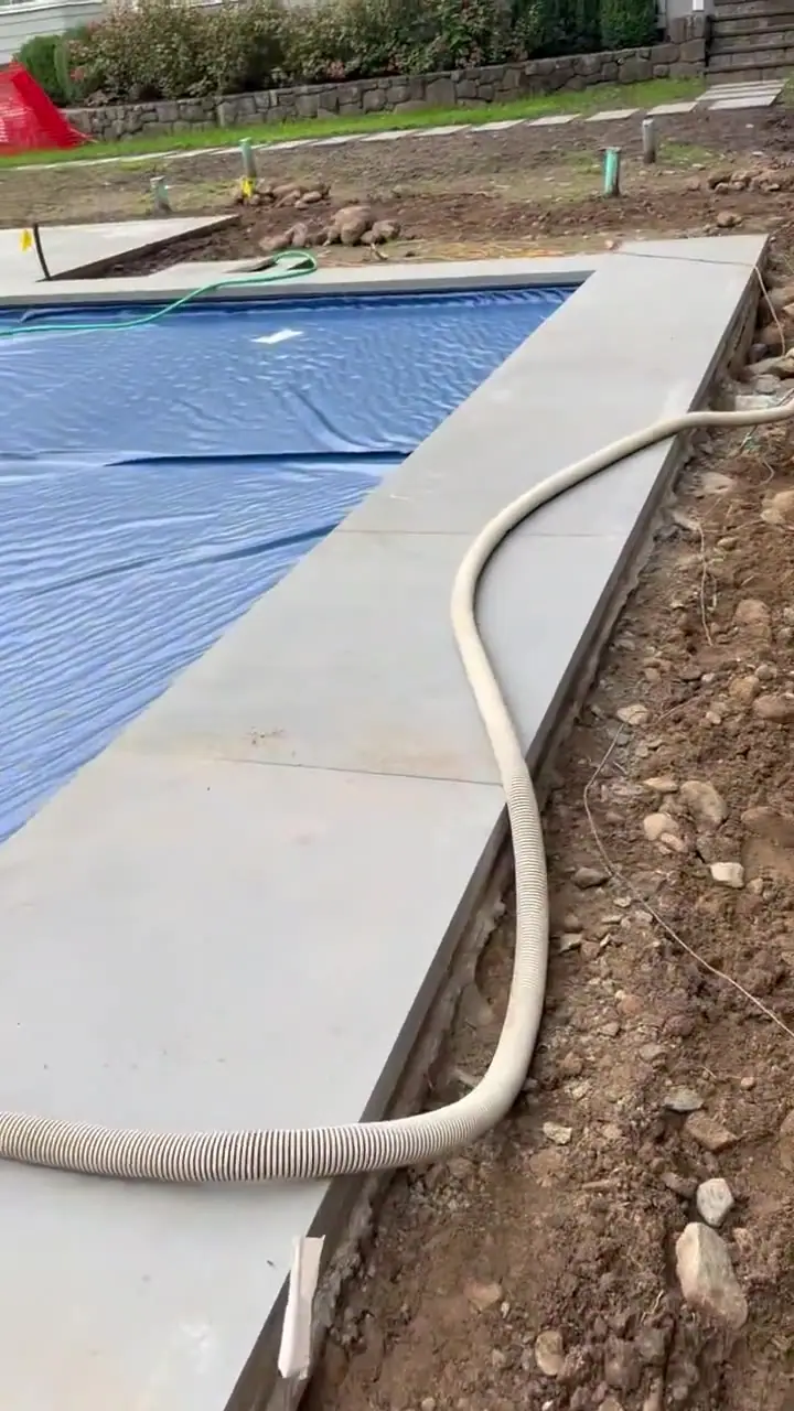 A cab view of the loader bucket working the prepared soil beside the pool at the New Canaan, CT project before Monday's laser-level finish work