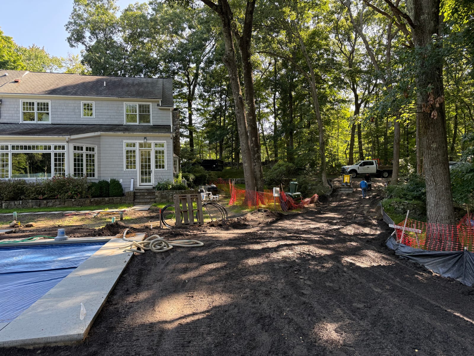 View toward the house and covered pool at the New Canaan, CT sod project, with materials staged and a truck up the access road