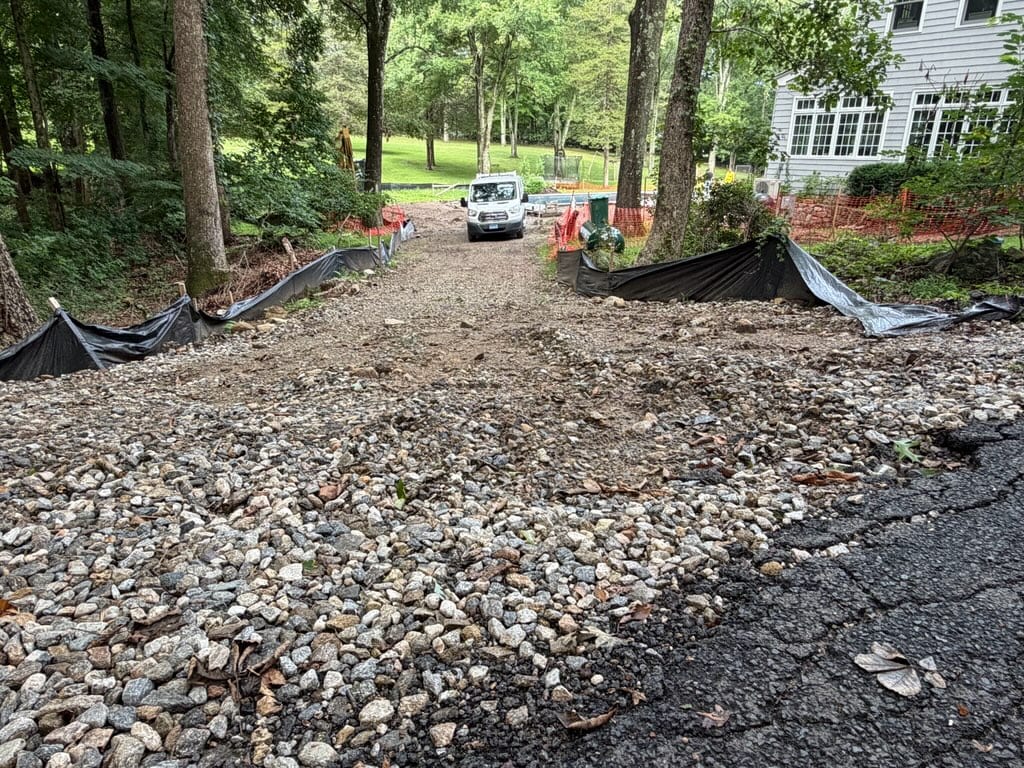 Steep gravel access road leading into the New Canaan project area before grading and sod installation