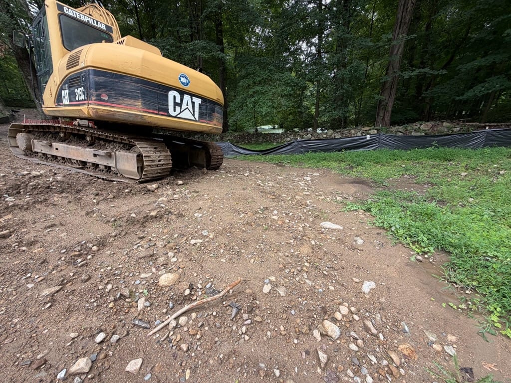 Excavator beside exposed rocky soil at the New Canaan site before CT Sod begins grading and sod work