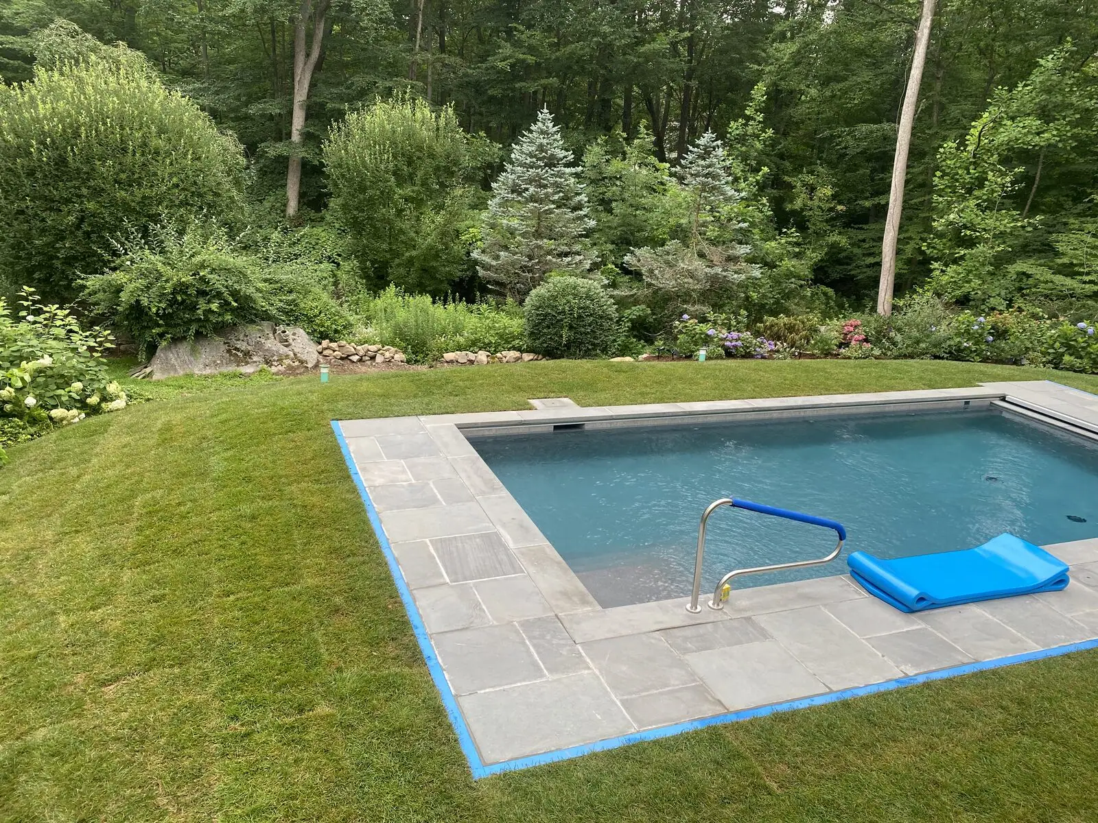Fresh sod meeting the stone pool coping flush in New Canaan, CT