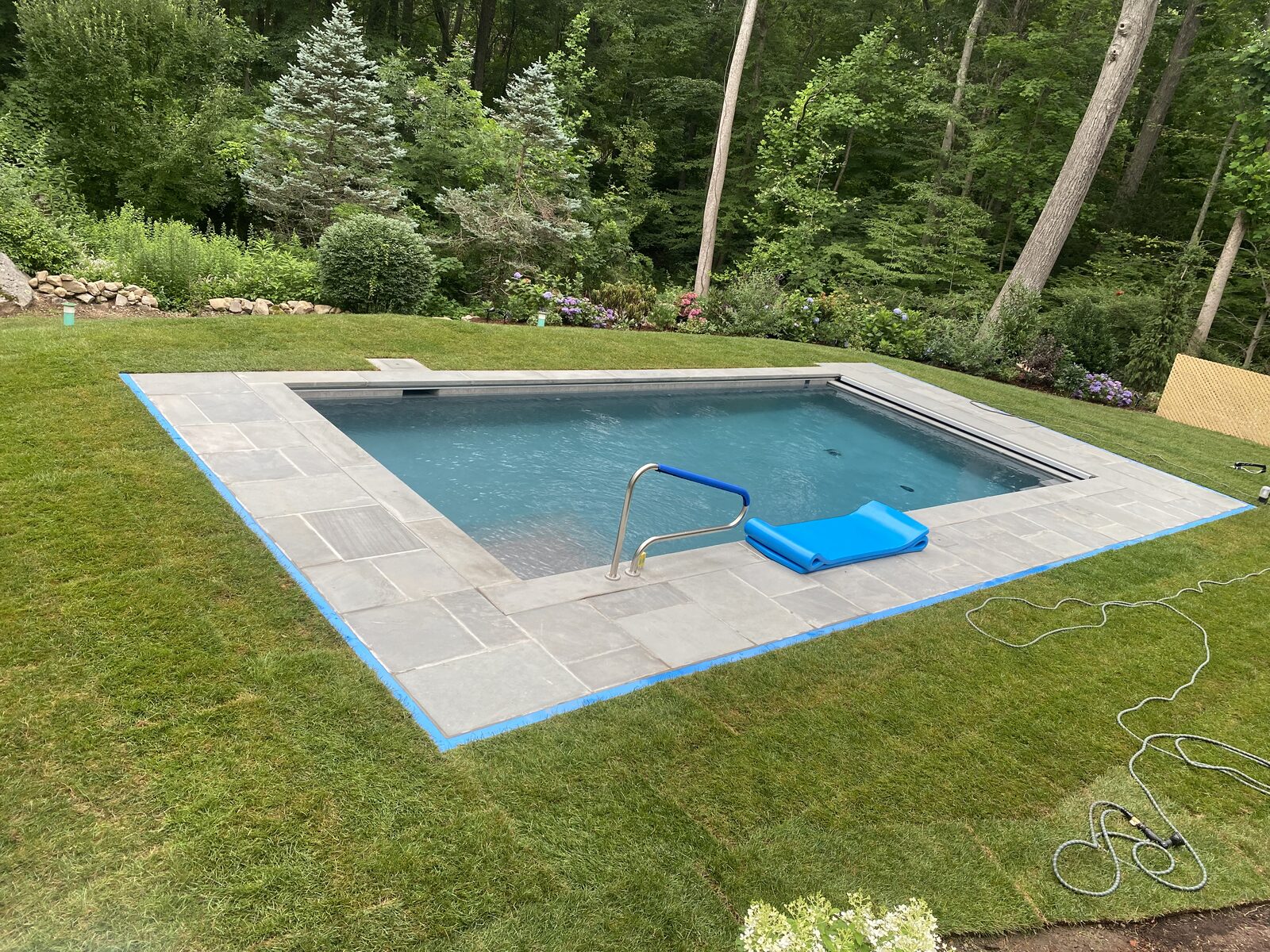 Fresh Kentucky bluegrass sod wrapping a bluestone pool deck at a CT Sod job in New Canaan, CT