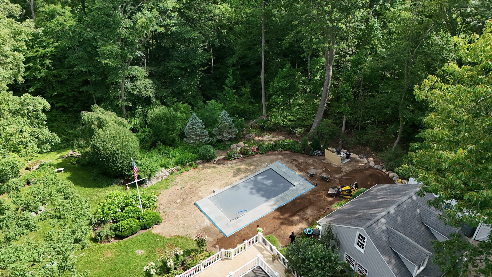 Aerial view of a New Canaan, CT backyard with fresh topsoil graded smooth around a new covered pool, prepped and ready for sod installation