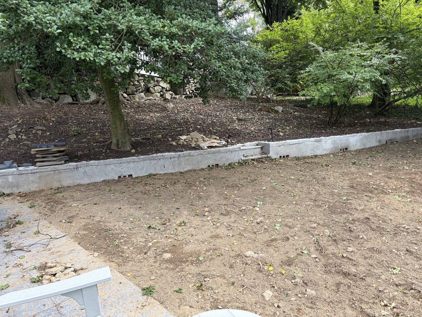 Bare lawn area beside the patio and retaining wall before sod installation in Norwalk, CT