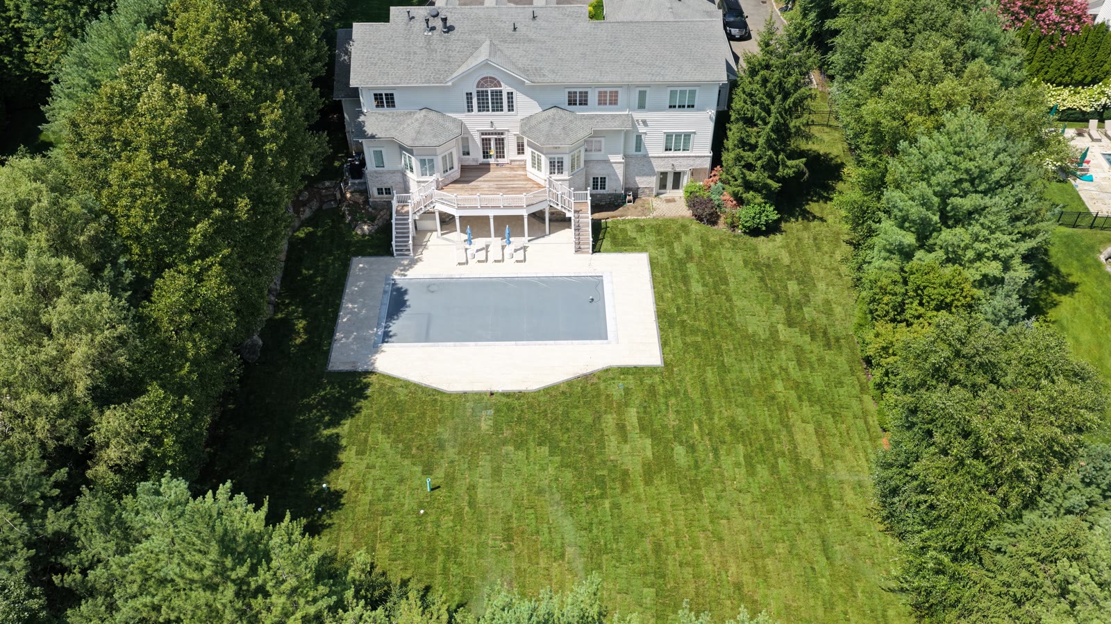 Fresh Kentucky bluegrass lawn across a Purchase, NY backyard estate after a full pool-construction regrade