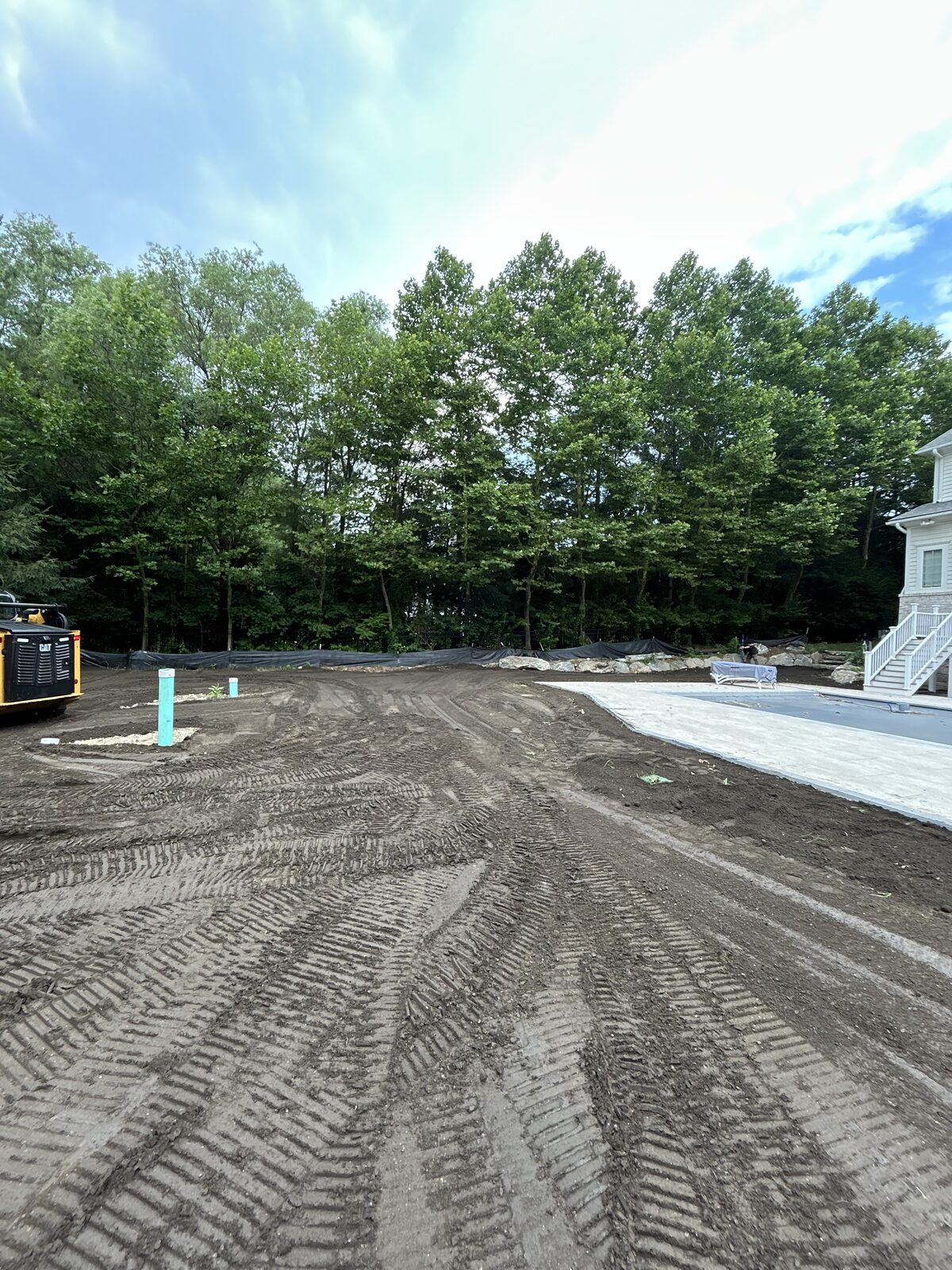 Tire tracks from heavy pool construction equipment pressed into the bare dirt yard of a Purchase, NY home
