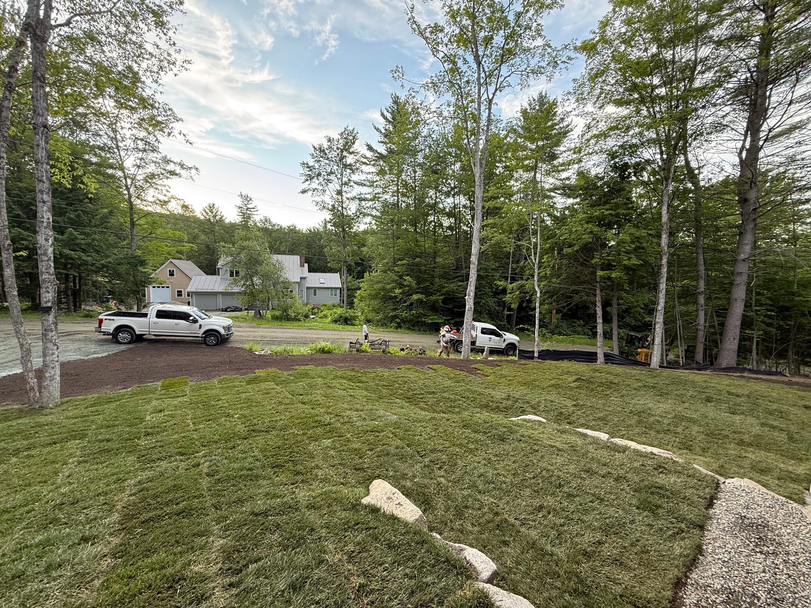Wide afternoon view of the completed lawn meeting the new gravel driveway, a CT Sod truck parked where the mud had been hours earlier