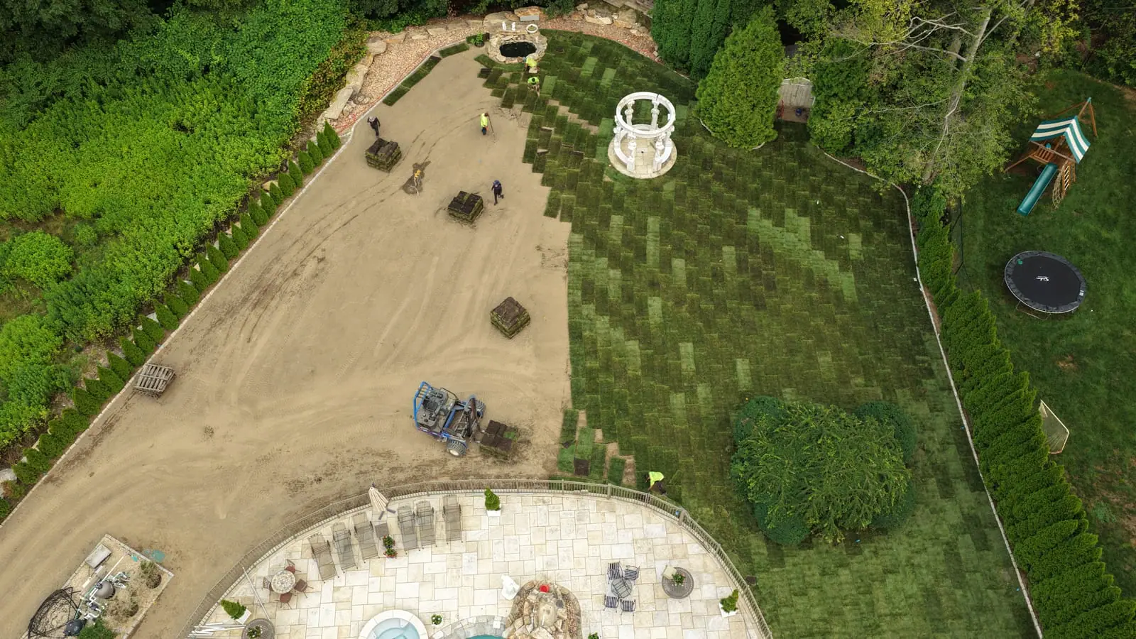 Overhead drone view of the CT Sod crew laying fresh sod rows around a white gazebo in Shelton, CT, the stair-stepped working edge advancing across the graded yard