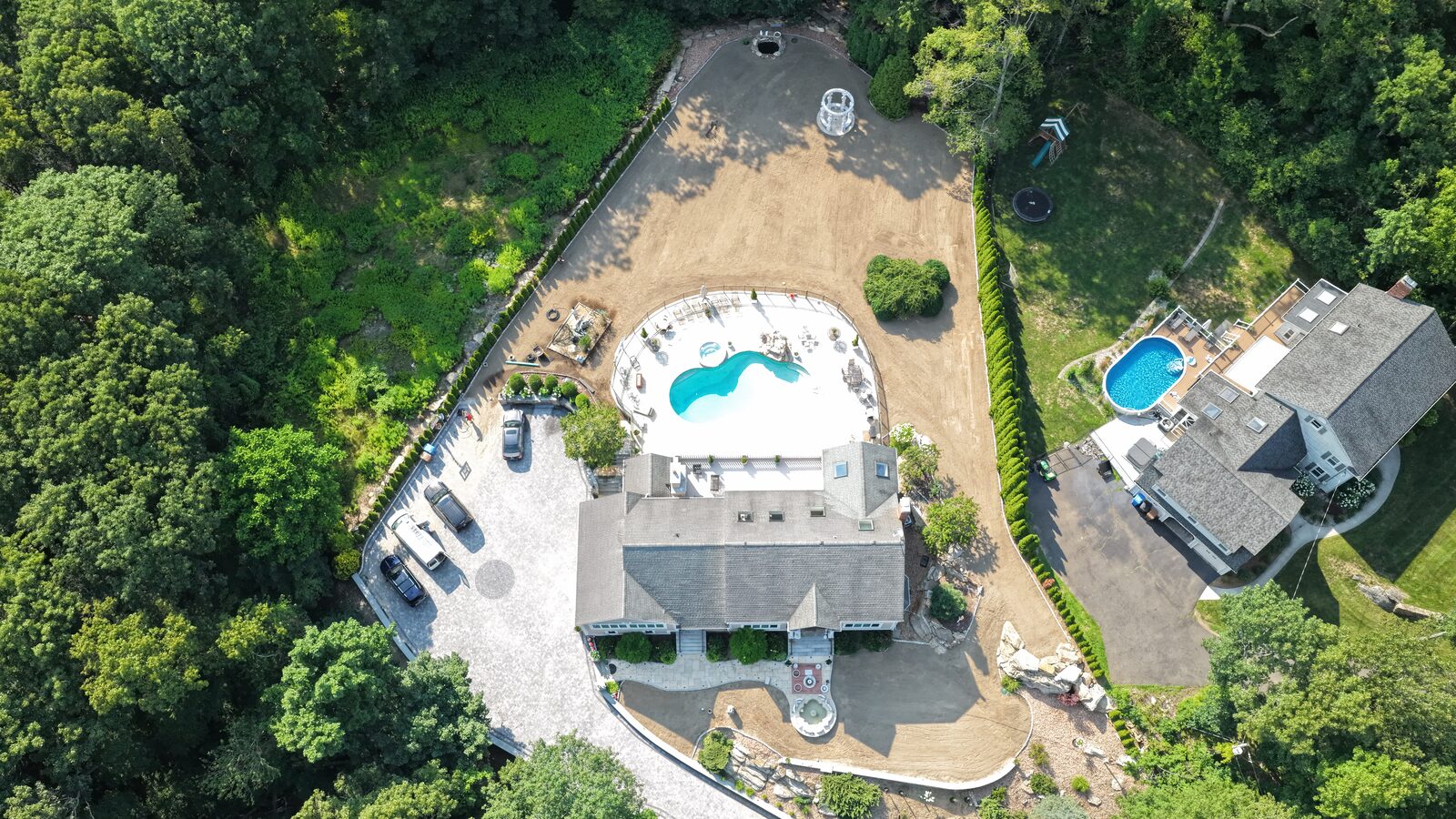 Overhead drone view of the finished sod prep in Shelton, CT — 17,000 square feet of smooth screened-topsoil finish grade wrapping the new pool, spa patio, and gazebo, ready for fresh sod