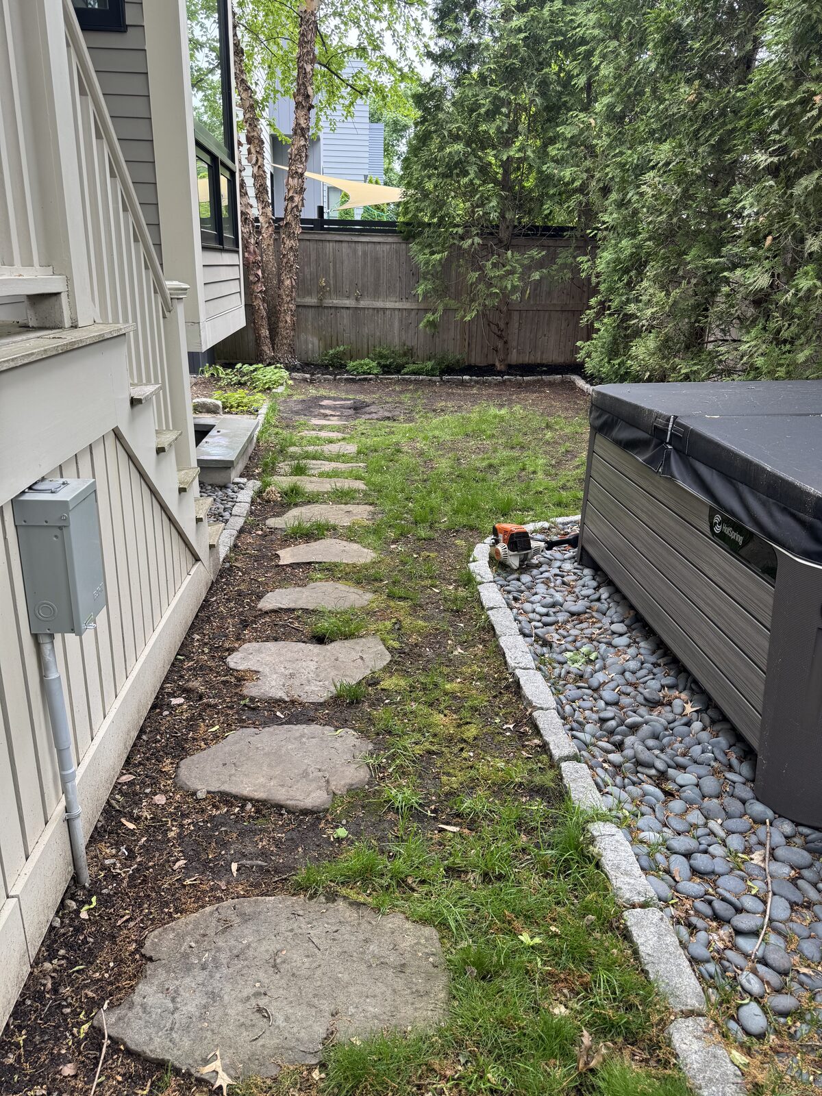 Before photo of a patchy Cambridge backyard with weedy lawn and a stepping-stone path before sod prep