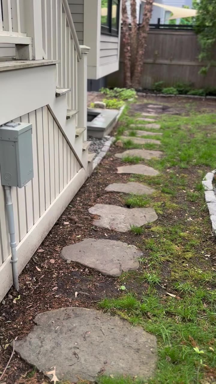 Walkthrough of the Cambridgeport backyard before prep — stepping-stone path, bare compacted strip along the foundation, and the weedy patches that finally pushed the homeowner to sod