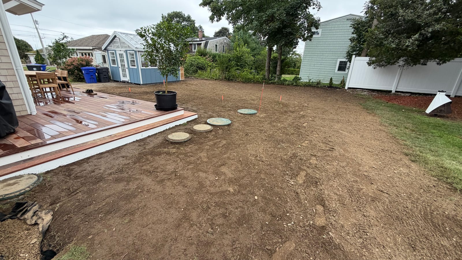 Graded backyard off the deck at a Warren, RI home with irrigation runs flagged out across the bare soil