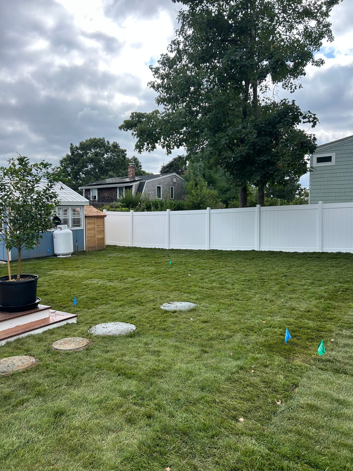 Finished back yard in Warren, RI — fresh-cut sod laid around stepping stones and planting beds inside a white fence