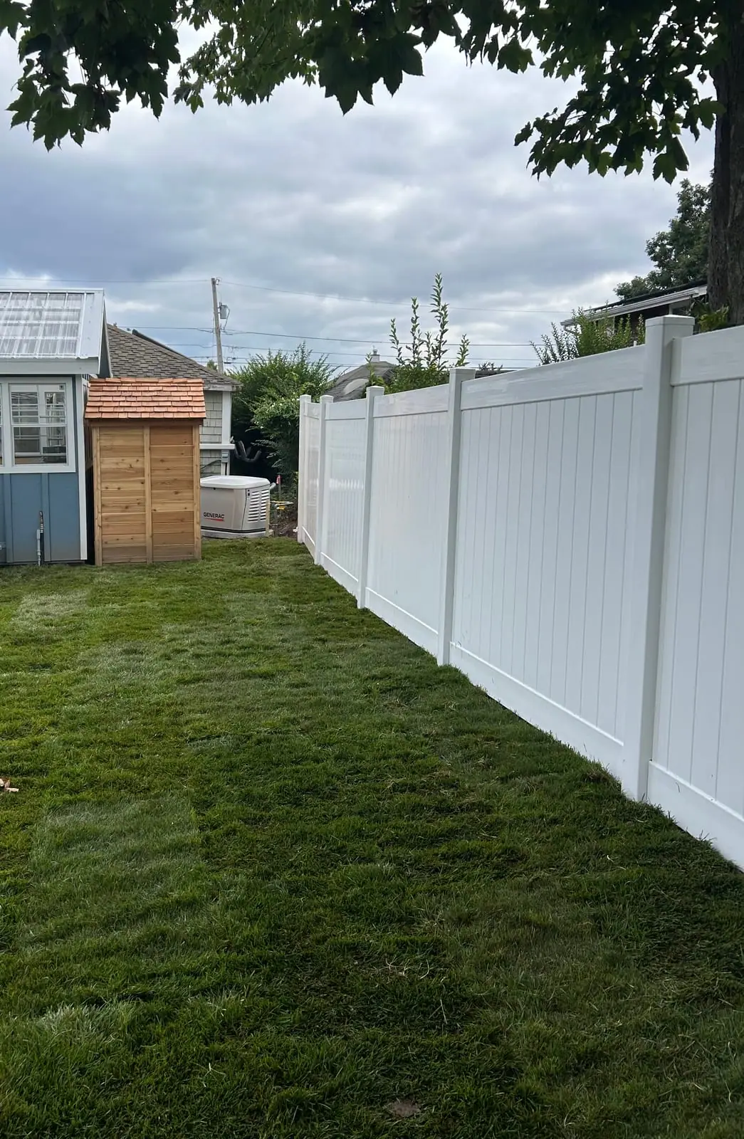 Fresh-cut sod installed along the white fence line in the back yard of the Warren, RI project