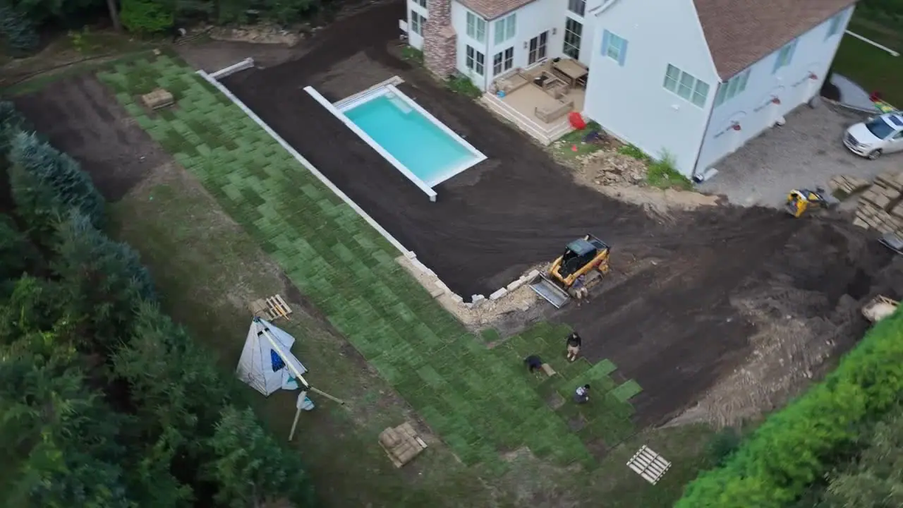 5:11 p.m. — straight over the crew laying rows along the retaining wall at the pool level. If you want to see how sod should go down — staggered seams, joints pushed tight, no gaps — this is the clip