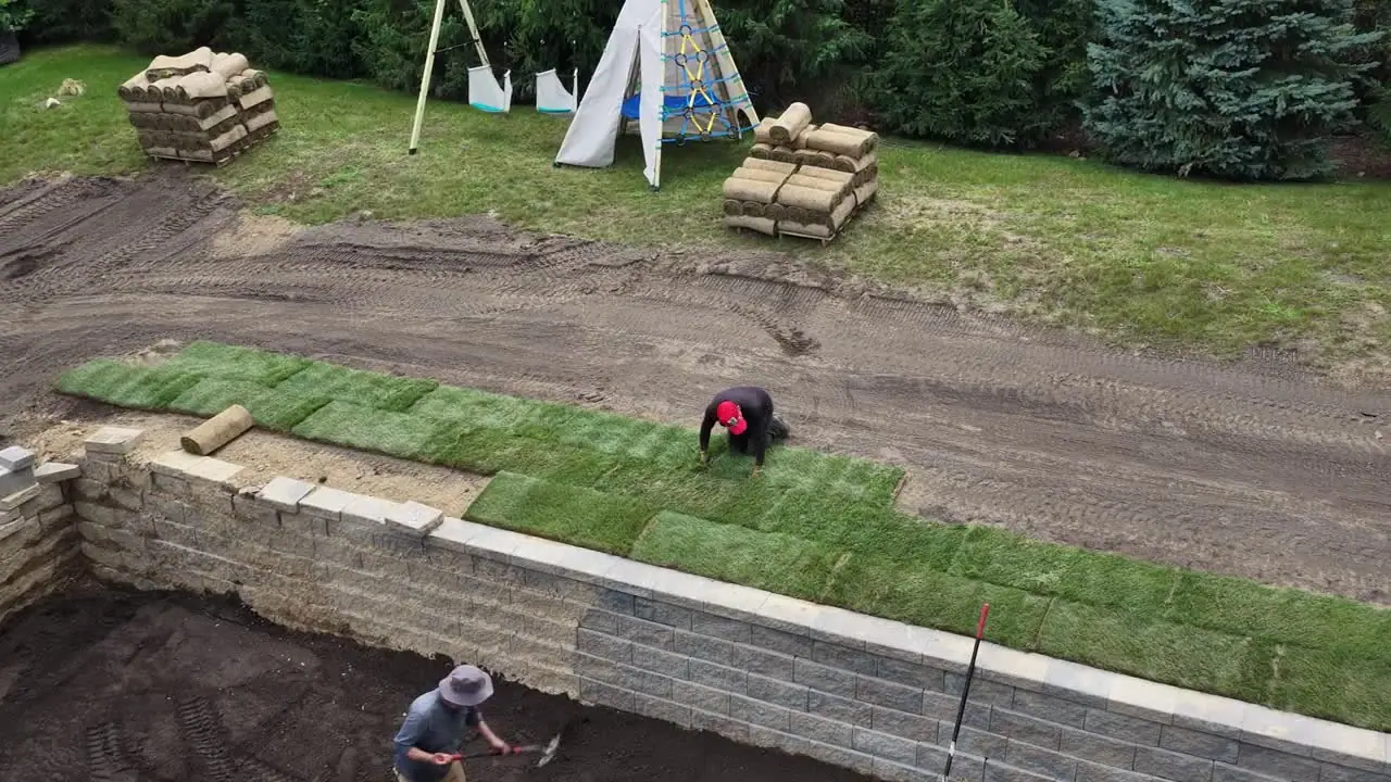 4:09 p.m. — grading and laying overlap: the machines finish their last passes while rolls keep coming off the pallets. That overlap is the only way 8,000 square feet fits in one working day