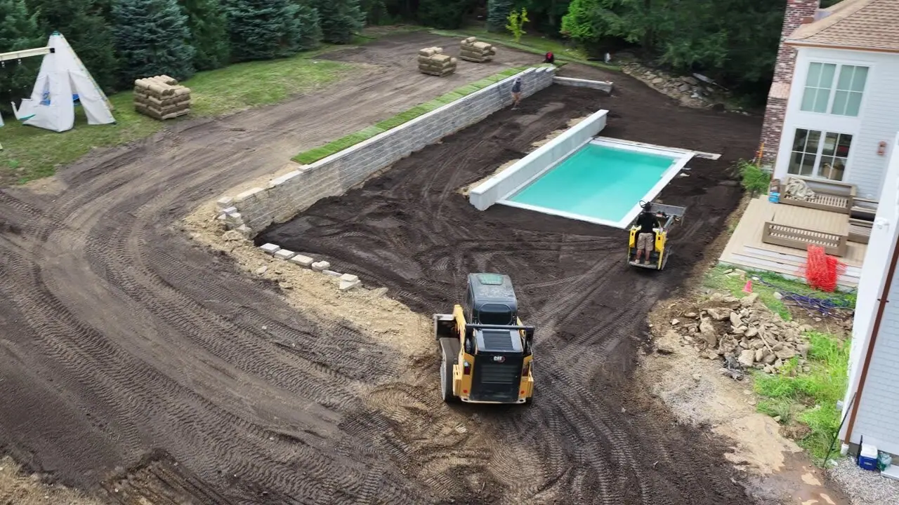 The long pass — staging rows, the graded yard, the pool wall, and the whole 8,000-square-foot footprint ready for sod
