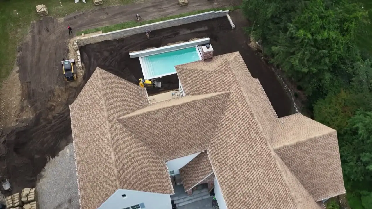 4:03 p.m. — straight down over the property. From this height you can read the whole plan: pool at the center, graded fields on both sides, and pallets spotted around the yard so no roll gets carried farther than it has to be