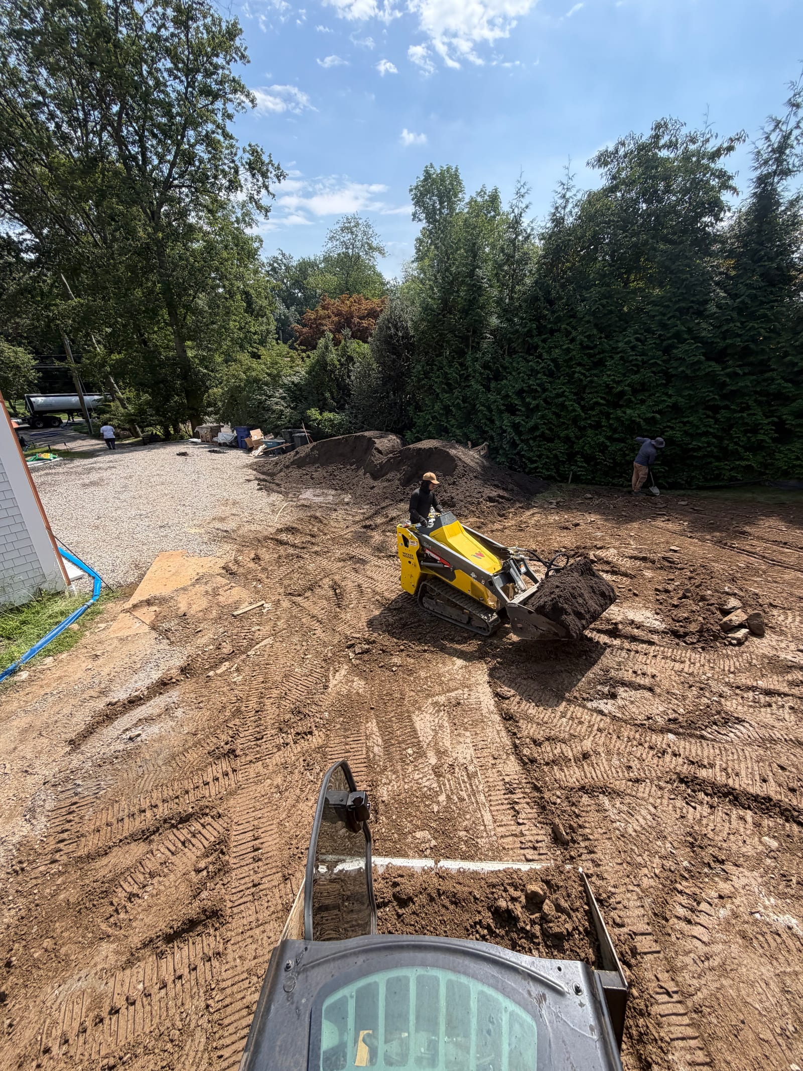 Excavator working across the rough lower-yard grade during the 8,000 square foot Westport sod installation