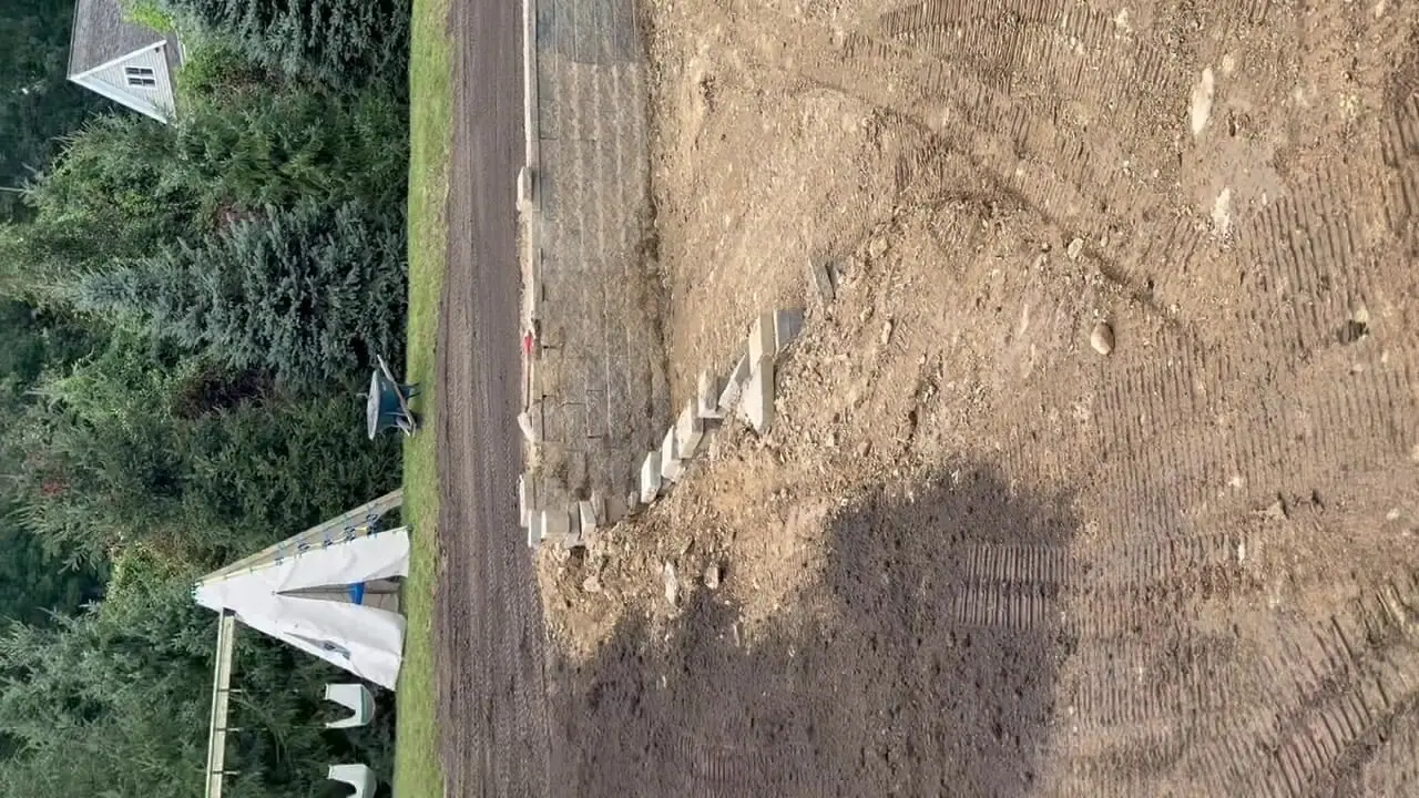 1:42 p.m. Friday in Westport — a full pass across the backyard showing screened topsoil spread on the upper lawn and the lower pool-side grade still open