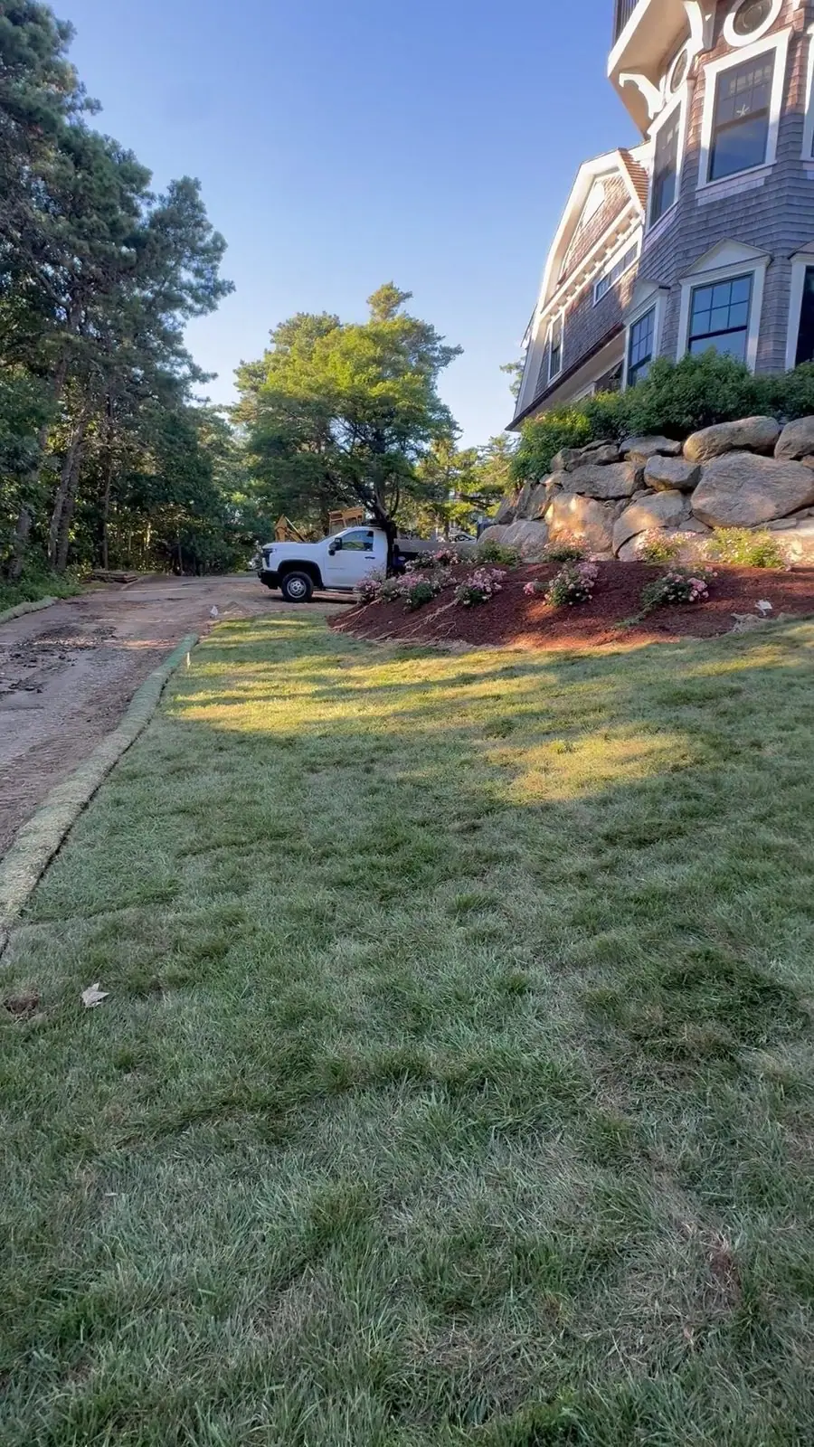 The lower lawn on install evening, new sod running from the drive up toward the house
