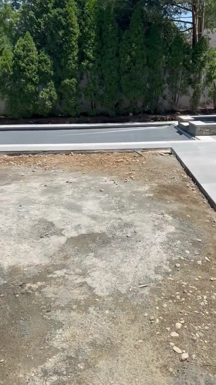 The homeowner walks the yard the way the pool builder left it — thin dusty grade, gravel, and patches of hardened concrete slurry where the lawn is supposed to go