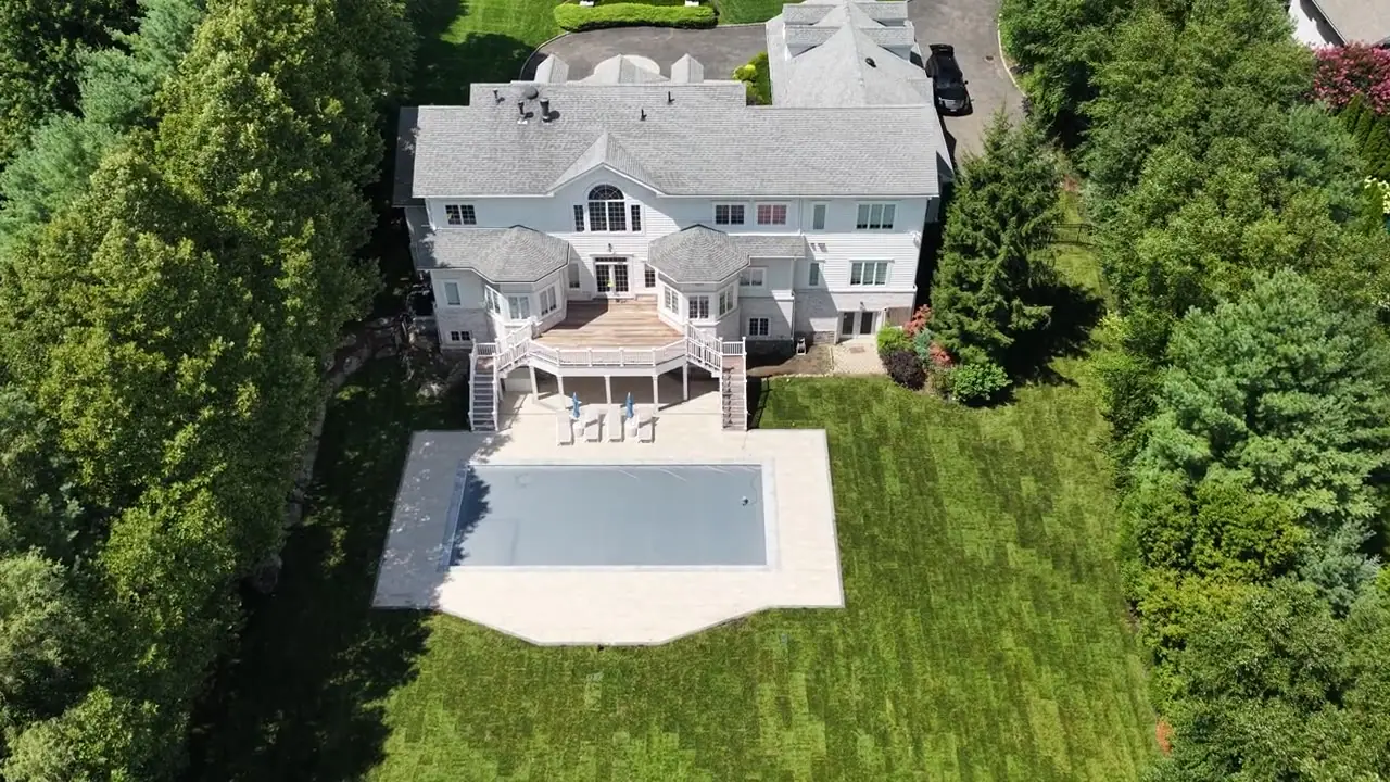 Aerial reveal of a finished 12,000 square foot Kentucky bluegrass sod lawn wrapping the new pool and patio of a Purchase, NY estate