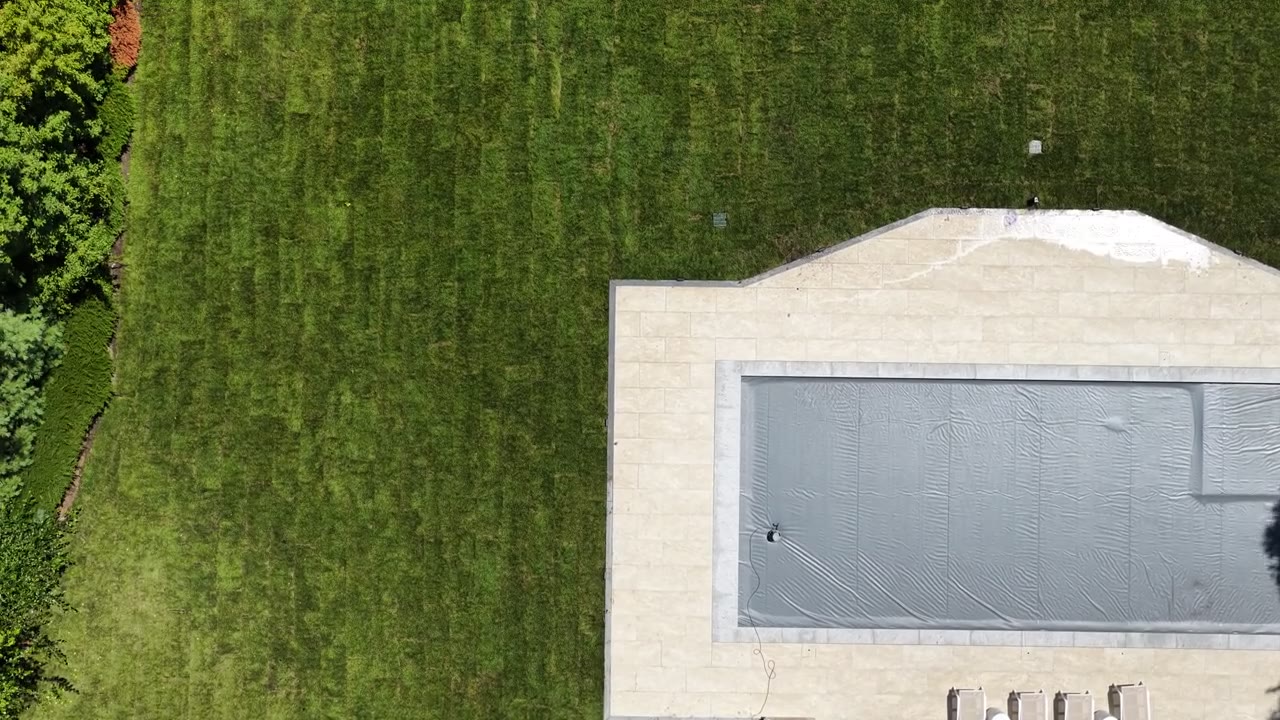 A slow straight-down pass across the back lawn — fresh rolls still showing their seams, every one of them tight to the next