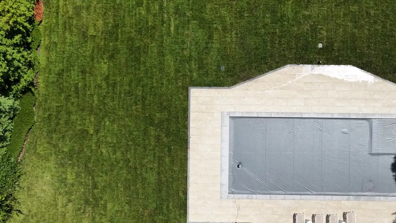 A slow straight-down pass across the back lawn — fresh rolls still showing their seams, every one of them tight to the next