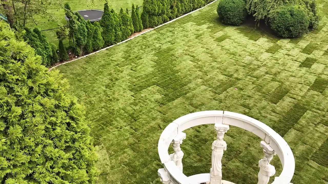 Drone rising over the white gazebo in Shelton, CT — statue columns and fresh checkerboard sod on the slope behind the pool