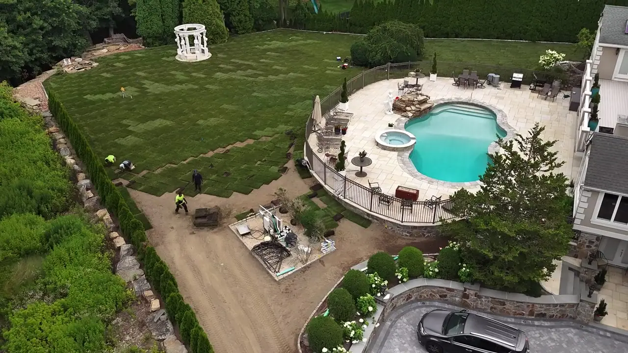 Drone view of the Shelton, CT install at mid-morning — crew and forklift working the last open stretch of grade while finished sod rows fill in behind them