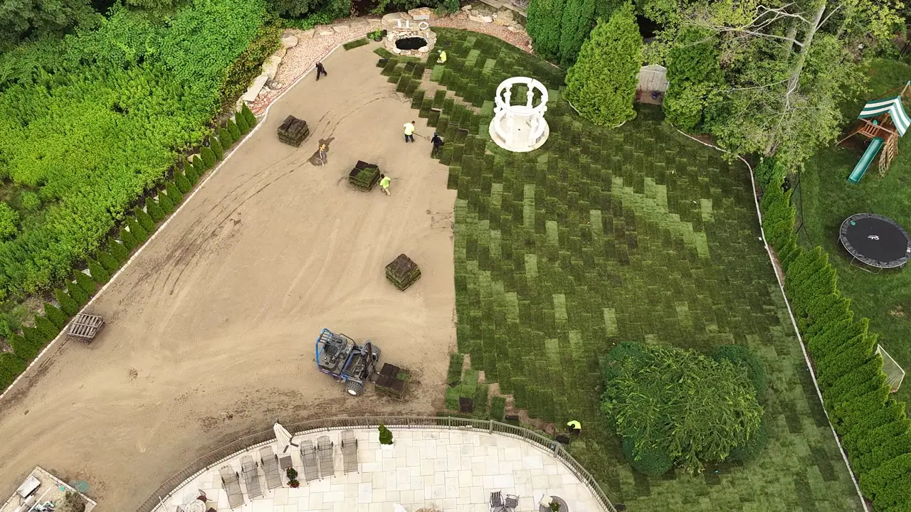 Aerial morning view of the CT Sod crew laying fresh sod around the white gazebo in Shelton, CT, pallets staged across the graded yard