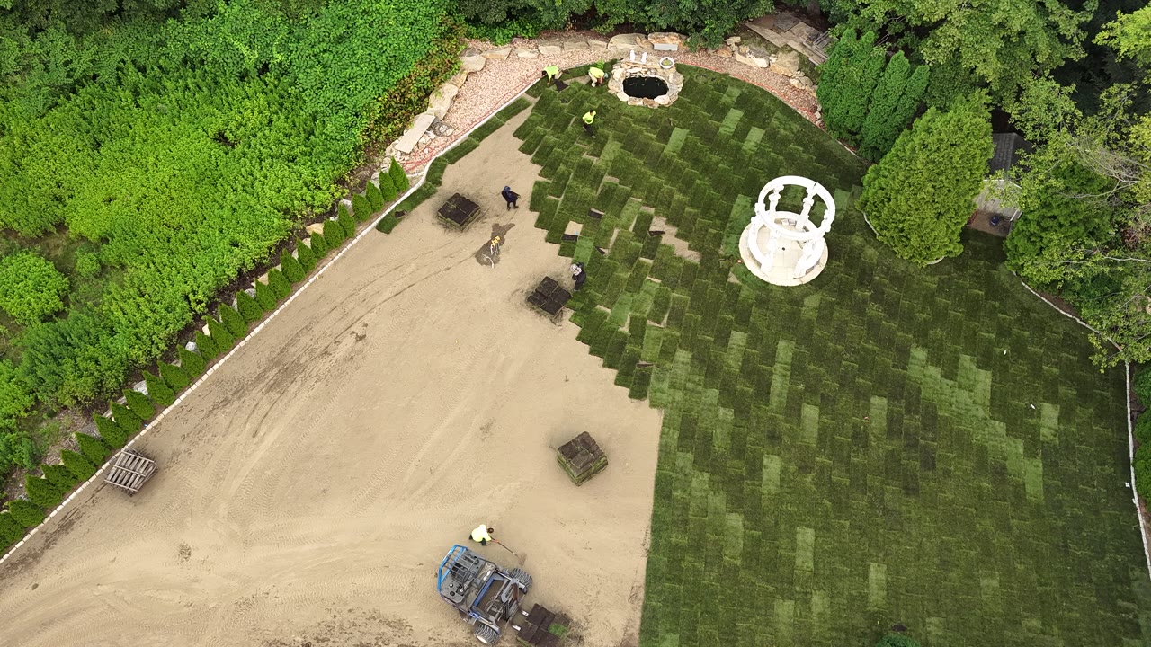 A flyover of the whole yard at the halfway mark — fresh sod wrapping the gazebo and water feature as the bare grade shrinks
