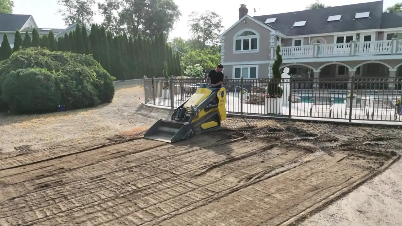 Screened topsoil going down in strips across the graded yard — the crew works around the gazebo while the finish grade takes shape between the pool fence and the tree line