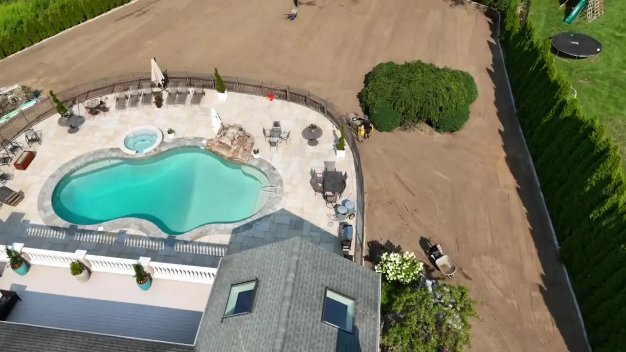 Flyover of the graded yard — 17,000 square feet of screened topsoil worked to an even finish grade between the pool fence and the privacy hedges